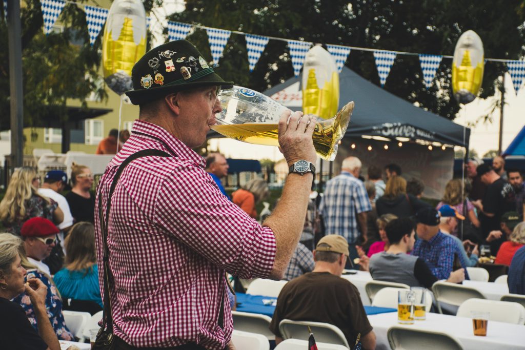 Man in lederhosen enjoying a large beer mug at an Oktoberfest celebration -- the largest beer festival.