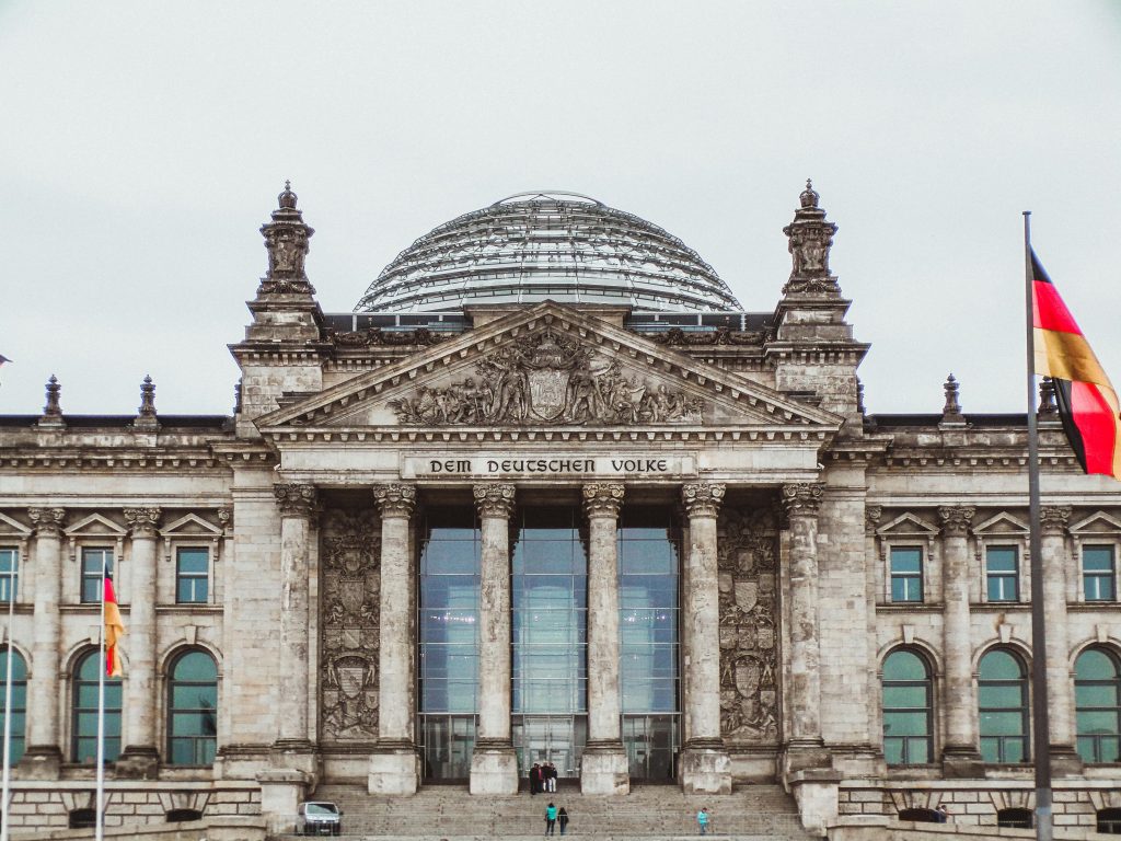 Front view of the historic Reichstag Building in Berlin, Germany, featuring prominent German flags.