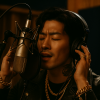 HelloGerman cover image for the song "Woher kommst du". The image shows an attractive Asian man in front of a professional microphone. He is holding his headphones while singing.